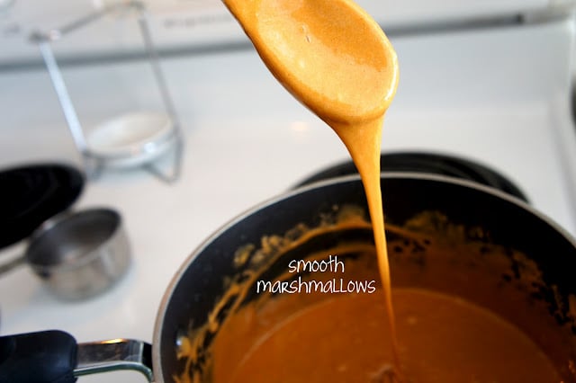 A spoon dripping melted marshmallows over a pan of melted marshmallows, demonstrating smooth marshmallows