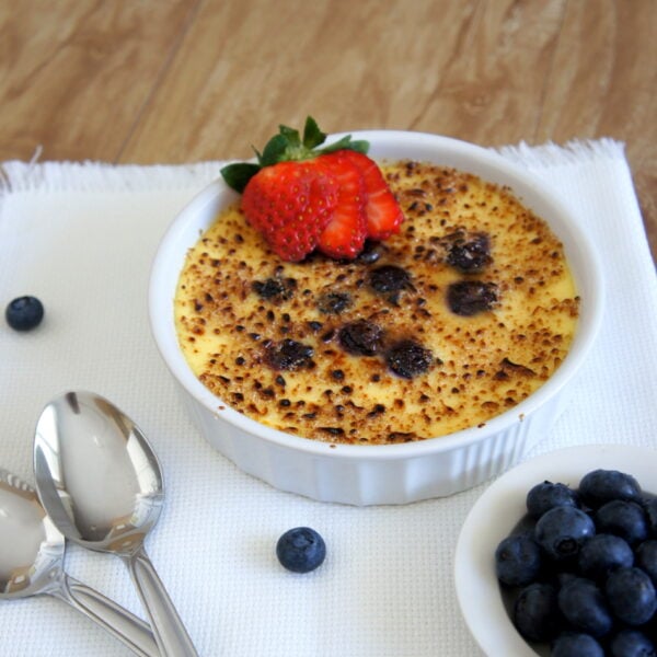 A Blueberry Cheesecake Creme Brûlée topped with a sliced strawberry