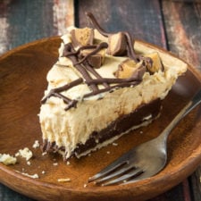 A slice of Chocolate Bottomed Peanut Butter Pie with a bite taken from it displayed on a plate