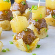 A close up of meatballs on an individual mini crust with a pineapple on top and held together with a toothpick