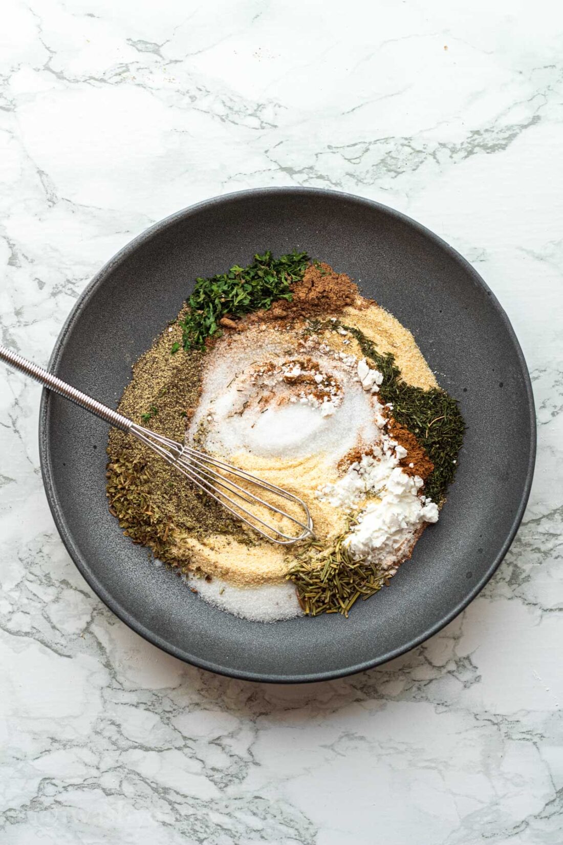 Swirled spices in a black dish with whisk.
