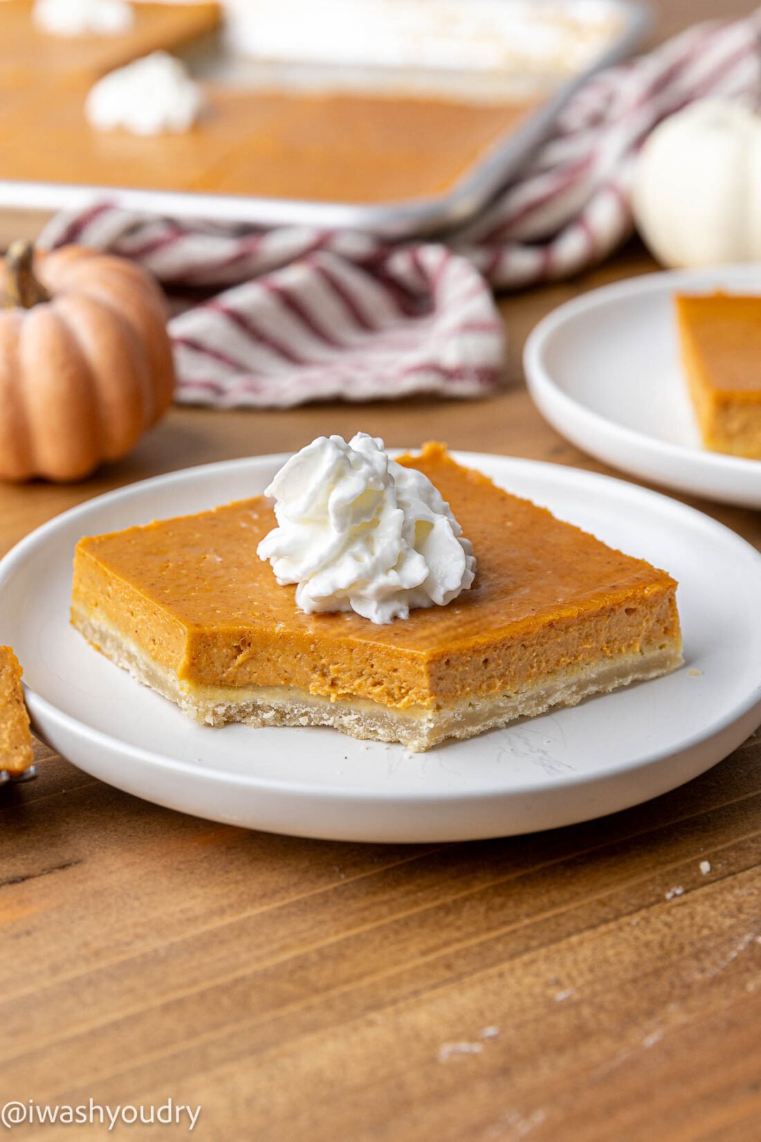 Slice of pumpkin pie bar with bite removed on white plate.